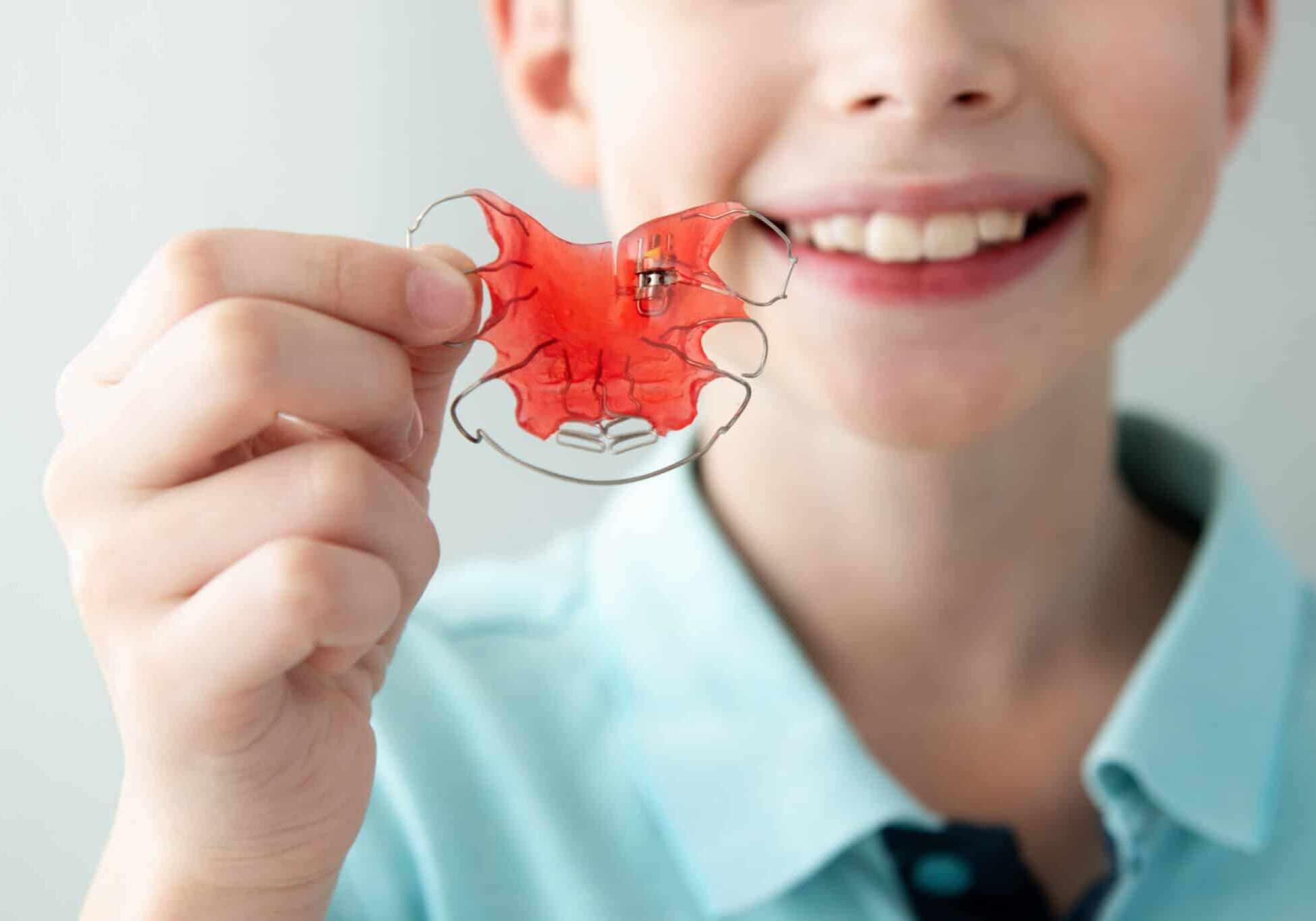 Teeth Dental Plate for Children. Child Holding Red Orthodontic Braces Retainer Fixer for Aligning Teeth and Expansioin Jaw