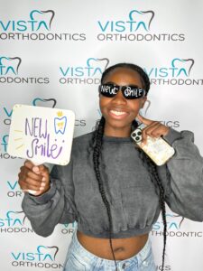 Girl with straight teeth holding sign that says new smile