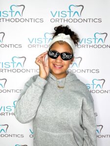 Girl with straightened teeth posing with glasses that say new smile