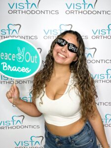 Girl smiling holding sign that says peace out braces